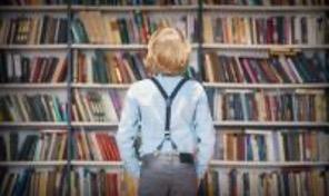 Chłopiec stojący przed księgozbiorem