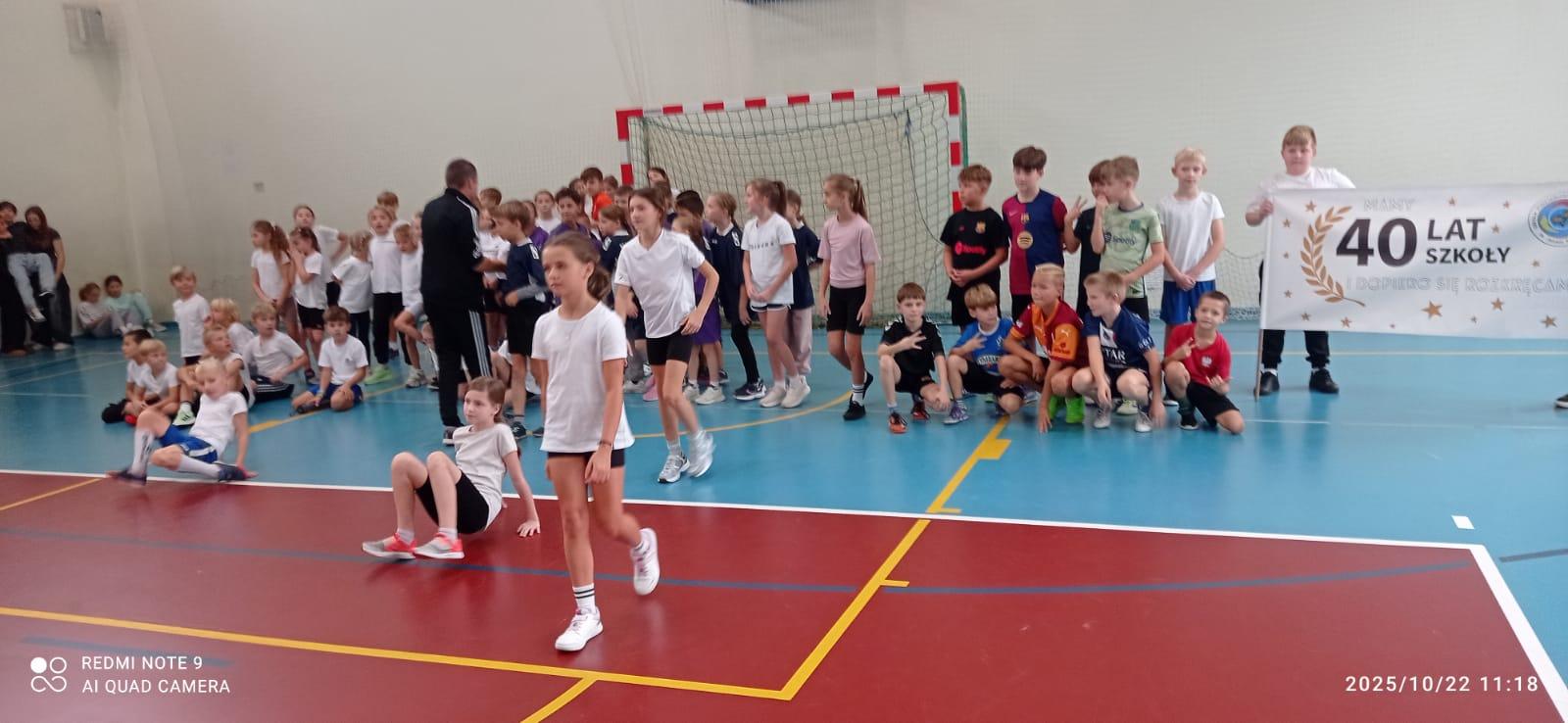  dzieci stoją w grupie na sali gimnastycznej