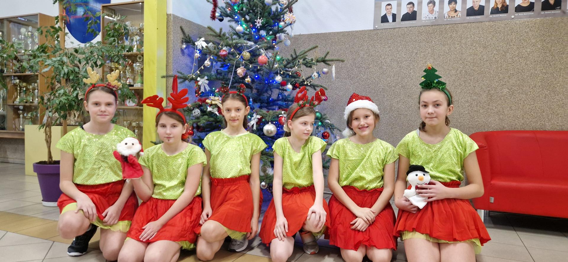 dzieci klęczą przed choinką